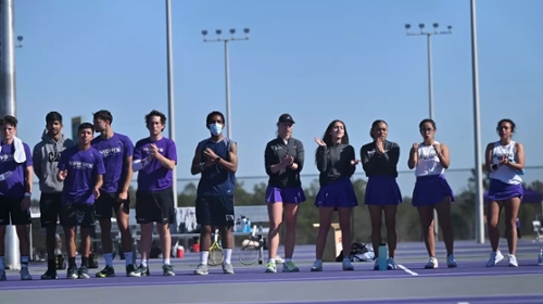 Knights tennis players cheering on their team from the sidelines. 